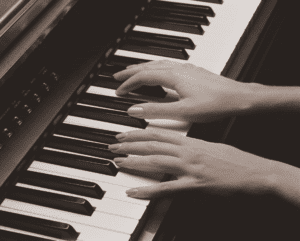 woman fingers playing piano in sepia toned image