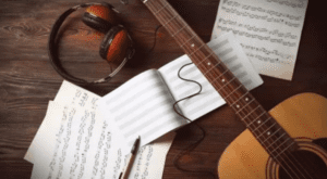 songwriting session with guitar and sheet music