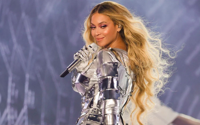 Beyonce singing confidently on stage in a silver outfit